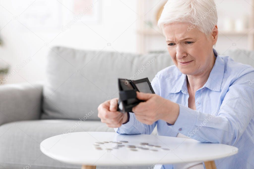 Poverty after retirement. Desperate senior woman shaking out last coins from wallet