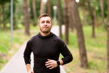 Koşan adam yolda koşuyor, kameraya bakıyor.