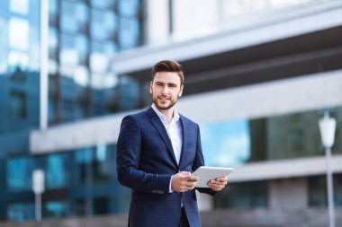 Şehir merkezindeki işlek caddede tablet bilgisayarlı bir ofis çalışanı.