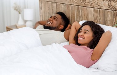 Neşeli Afrikalı çift yatakta uzanıyor.