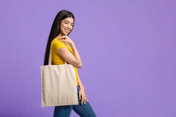 Eco Fashion. alegre ásia menina segurando branco sacola sobre roxo fundo — Fotografia de Stock