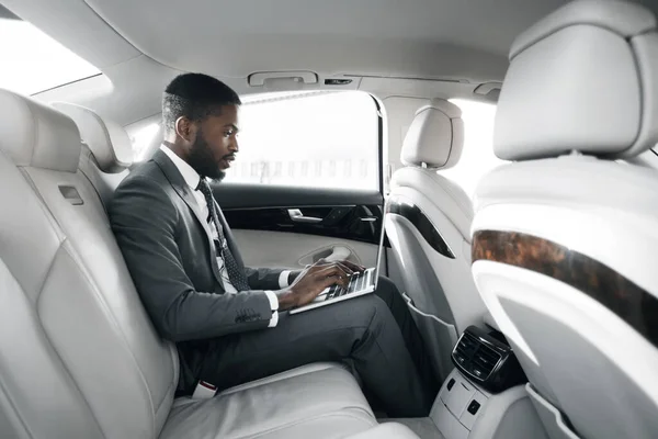 Afroamerikanischer Geschäftsmann arbeitet am Laptop im Auto — Stockfoto