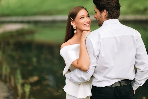 Feliz novia sonriendo al novio abrazando la ceremonia de celebración en el parque — Foto de Stock