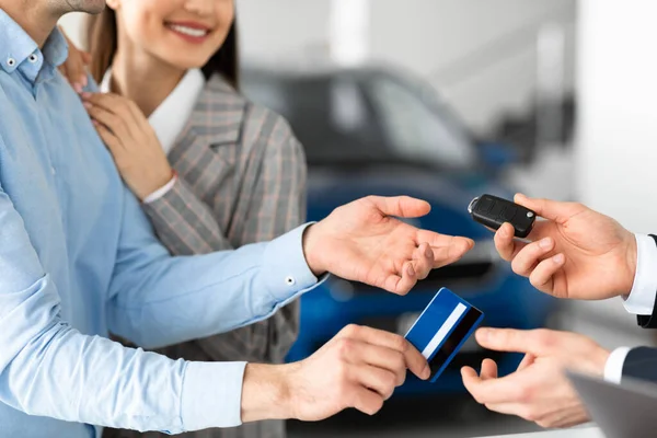 Casal de compra de carro dando cartão de crédito ao vendedor — Fotografia de Stock