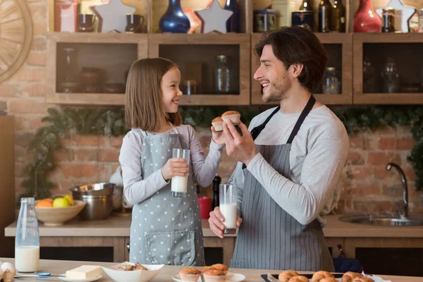 Mutlu kız ve babası mutfakta kek yiyip süt içiyorlar. — Stok fotoğraf