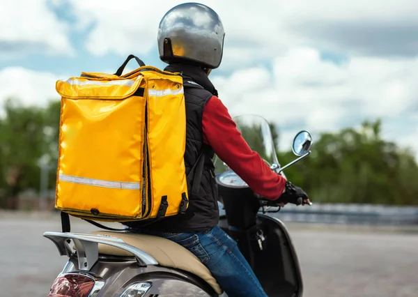 Mensajero de entrega de alimentos con mochila amarilla que monta la motocicleta al aire libre, vista trasera — Foto de Stock