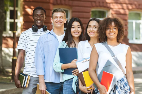 Grupp av leende mångkulturella studenter poserar nära universitetsområdet — Stockfoto
