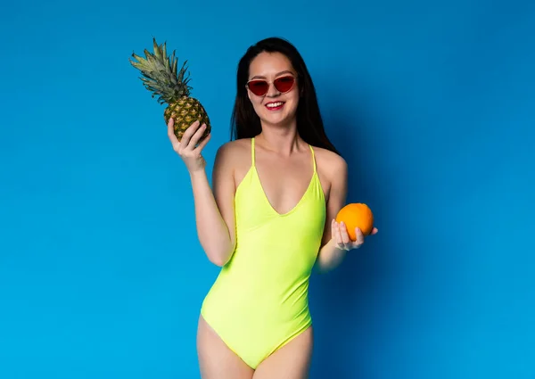 Dieta de Verão. Menina asiática bonita em maiô segurando frutas exóticas em mãos — Fotografia de Stock