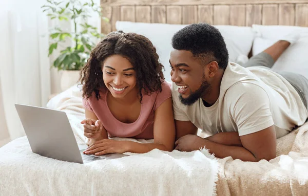 Lachendes schwarzes Paar schaut lustige Inhalte auf Laptop — Stockfoto