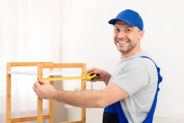 Profesyonel Marangoz, içeride bantla mobilya ölçüsü alıyor.