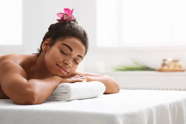 Menina africana pacífica deitada de barriga no spa — Fotografia de Stock