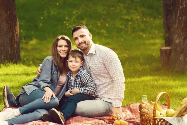 Família feliz com criança bonita desfrutando de seu tempo no piquenique no parque, espaço em branco — Fotografia de Stock