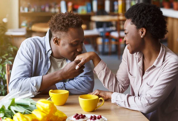 アフリカ系アメリカ人男接吻彼の最愛の女の子手でテーブルで現代的なカフェ — ストック写真