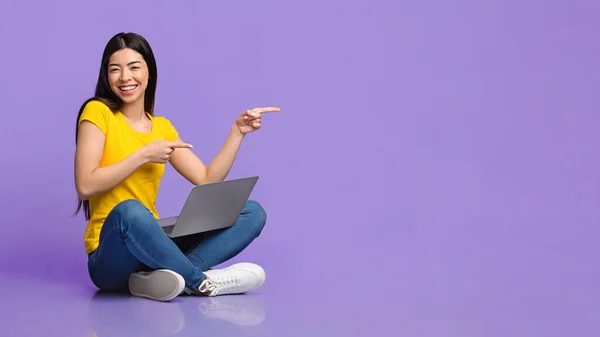 Különleges ajánlat. Vidám ázsiai lány ül laptoppal, mutatva a másolás tér — Stock Fotó