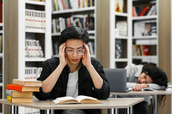 Dos estudiantes cansados estudiando en la biblioteca universitaria — Foto de Stock