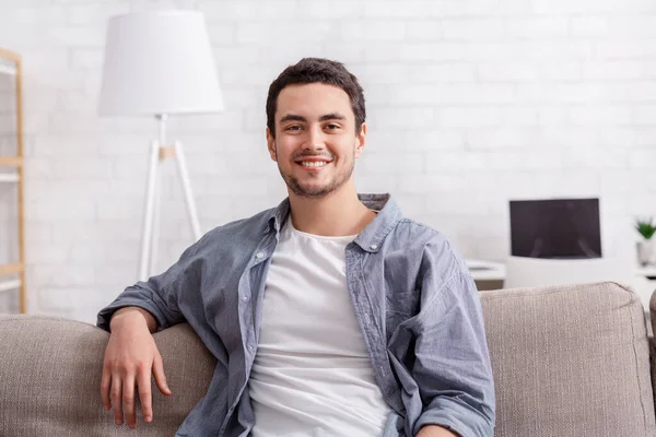 La vida en línea desde casa. Hombre atractivo sentado en el sofá —  Fotos de Stock