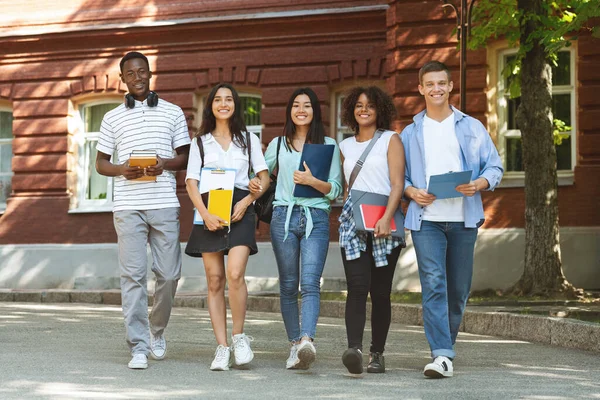 Estudantes multiculturais felizes caminhando juntos perto do campus universitário — Fotografia de Stock