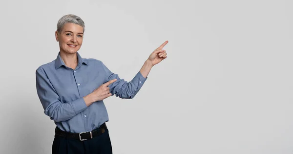 Lächelnde Geschäftsfrau mittleren Alters zeigt mit zwei Händen auf Kopierraum und empfiehlt etwas — Stockfoto