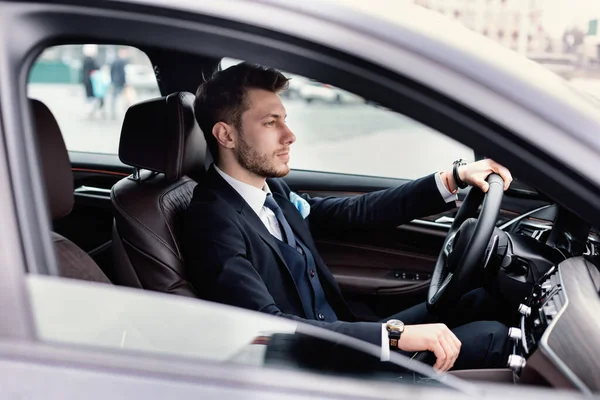 Orang yang percaya diri mengenakan setelan jas dan jam tangan mewah mengendarai mobil — Stok Foto