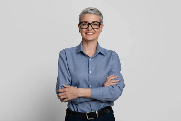 Retrato de atractiva mujer de negocios madura en gafas con estilo posando con los brazos cruzados —  Fotos de Stock