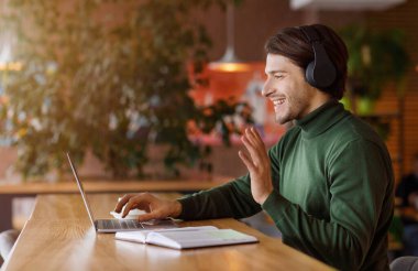 Telsiz kulaklıklı mutlu adam çevrimiçi konferans yapıyor.