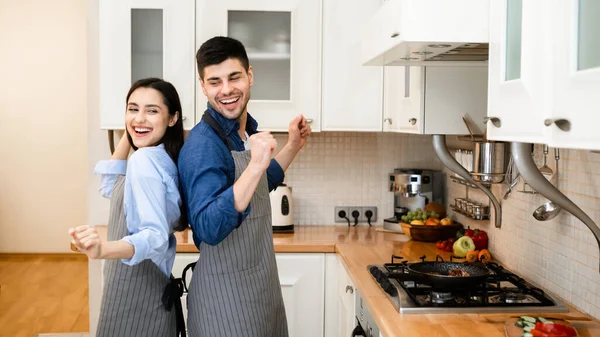 Молода пара готує вечерю вдома, танцює — стокове фото