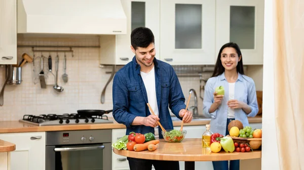 Casal feliz preparando salada juntos em casa — Fotografia de Stock
