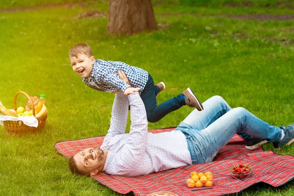 Pai alegre se divertindo com seu filho adorável durante piquenique na floresta — Fotografia de Stock