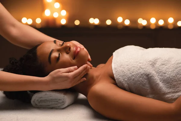 Relaxed african woman having face massage at spa — Stock Photo, Image