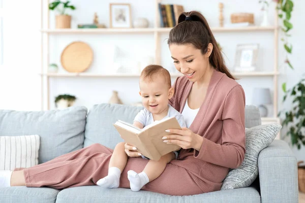 Early development. Millennial mom reading book to her toddler baby at home — Stock Photo, Image