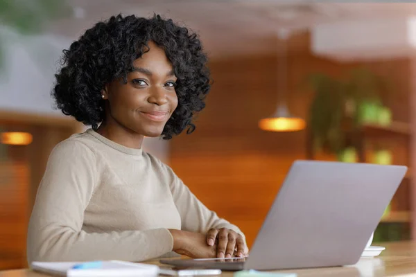 Sorridente signora nera utilizzando il computer portatile al caffè — Foto Stock