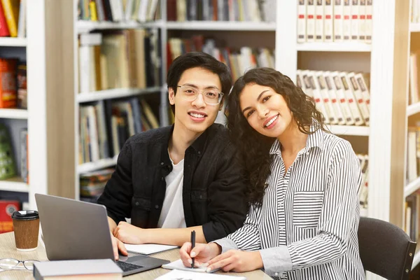 Uśmiechnięci wielonarodowi studenci uczą się w nowoczesnej bibliotece — Zdjęcie stockowe