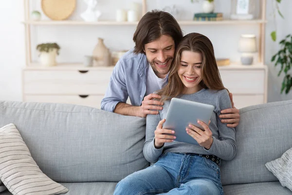 Mujer mostrando el contenido de su marido en la tableta digital, interior del hogar —  Fotos de Stock