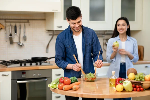 Feliz pareja preparando ensalada juntos en su acogedora casa — Foto de Stock