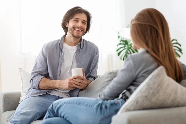 Щасливий хлопець п'є каву і розмовляє з дівчиною вдома — стокове фото
