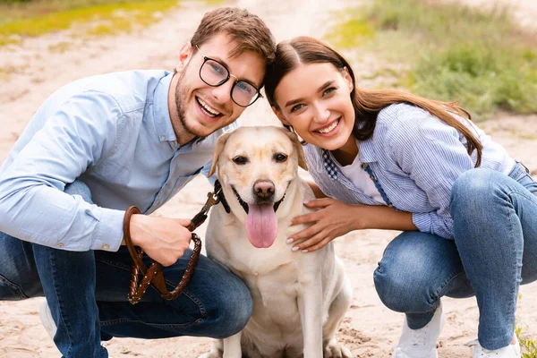 Porträtt av glada unga par kramar sin vackra hund — Stockfoto