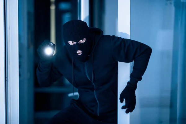 Thief breaking into apartment to steal, using flashlight — Stock Photo, Image