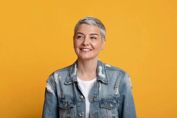 Portret van charmante volwassen vrouw in stijlvolle spijkerjasje over gele achtergrond — Stockfoto