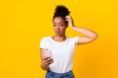 Kafası karışmış genç Afrikalı kadın cep telefonu kullanıyor.