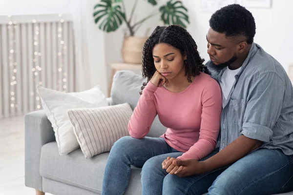 Gondoskodó afro férfi Vigasztalja depressziós feleségét otthon, ölelkezve és támogatva — Stock Fotó