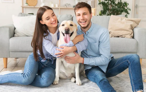 Jeunes amis heureux avec chien assis dans le salon — Photo