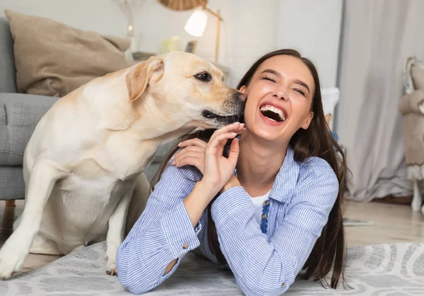 Joven mujer feliz con perro tirado en el suelo — Foto de Stock