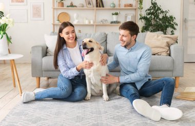 Köpekli mutlu çift oturma odasında oturuyor.