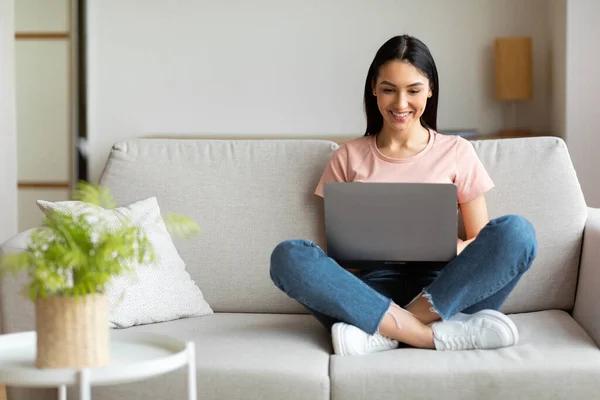 Lyckad frilansare kvinna som arbetar på laptop sitter på soffan inomhus — Stockfoto