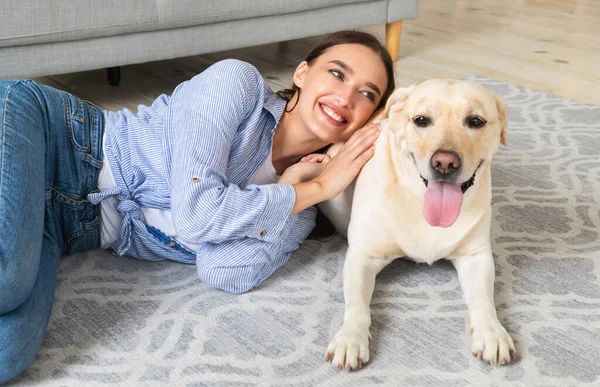 Ung lycklig kvinna med hund liggande på golvet — Stockfoto