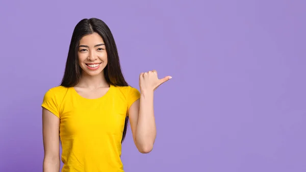 Dobrá nabídka. Usmívající se asijské dívka ukazující na kopírovat prostor s palcem nahoru — Stock fotografie