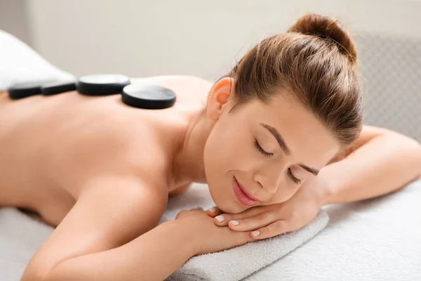 Slim attractive woman resting during hot stone massage — Stock Photo, Image
