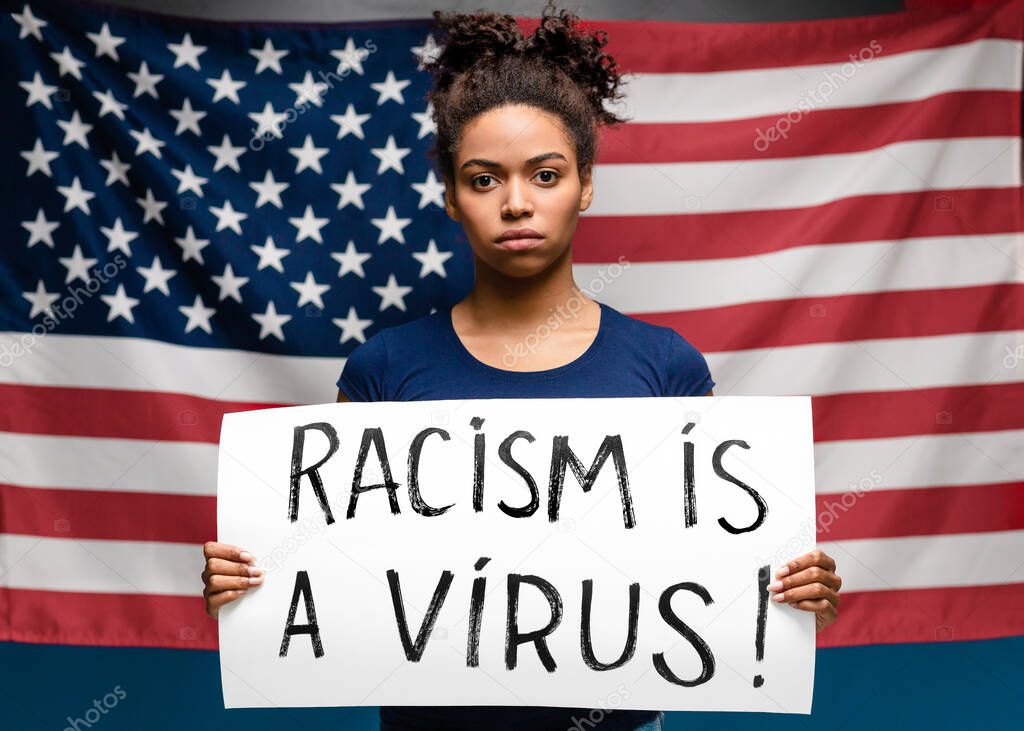 African woman standing with poster Racism is a virus