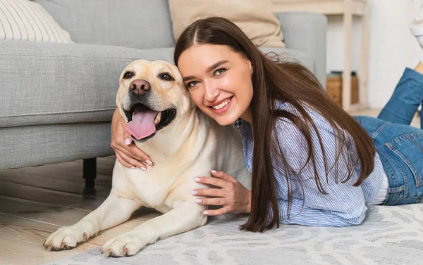 Ung lycklig kvinna med hund liggande på golvet — Stockfoto