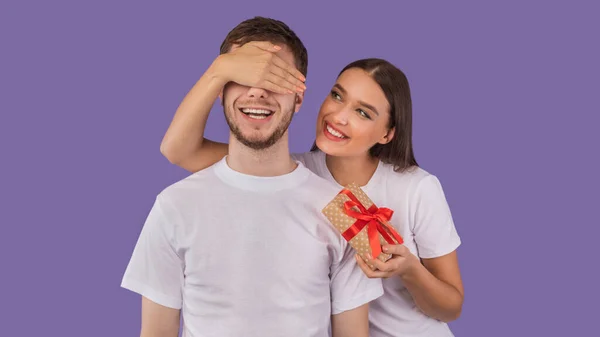 Chica cubriendo sus ojos de novio y dándole regalo — Foto de Stock